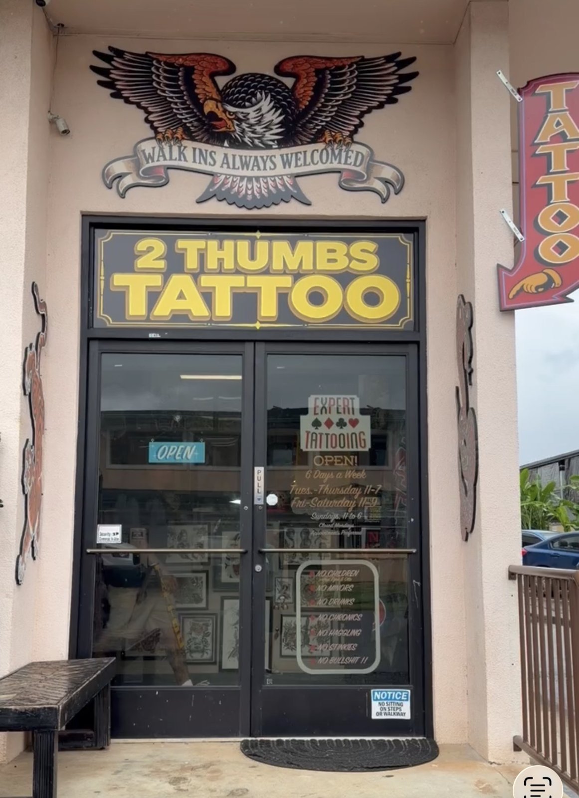 Front entrance of 2 Thumbs Tattoo, with the eagle sign and tattoo shop doors
